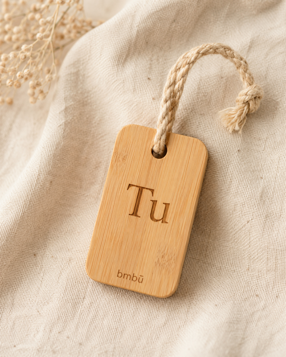 Custom bamboo key tag laser-engraved with a first name, on a bamboo-fibre cord